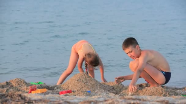 Niño y niña jugando en una arena en la playa — Vídeos de Stock