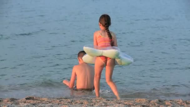 Petite fille et garçon jouant dans la mer — Video