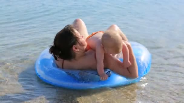 Madre con su pequeño bebé nadando en el mar con anillo inflado — Vídeo de stock