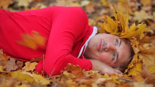 Hombre acostado en hojas de otoño — Vídeos de Stock