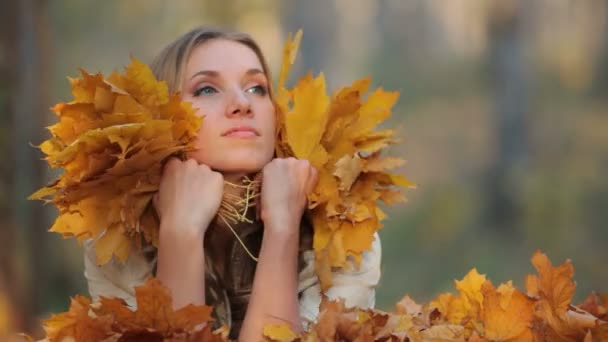 Jolie blonde allongée sur les feuilles tombées dans le parc — Video