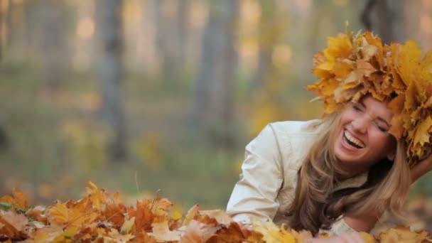 Jolie blonde allongée sur les feuilles tombées dans le parc — Video