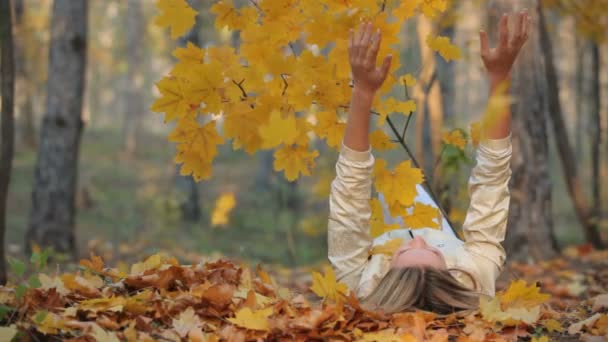 Bella bionda sdraiata sulle foglie cadute nel parco — Video Stock