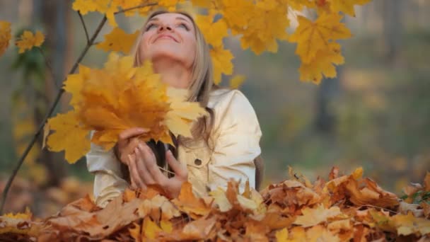 Hübsche Blondine liegt im Park auf dem fallenden Laub — Stockvideo