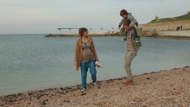 Семья из трех человек идет вдоль берега моря . — стоковое видео