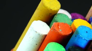 4K yakın plan renkli pastel boya kalemleri siyah arkaplanda izole edilmiş dönen plaka üzerinde çizim yapmak için