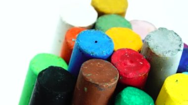 Beyaz arkaplanda izole edilmiş dönen plaka üzerinde çizim yapmak için renkli pastel boya kalemlerinin 4K yakın çekimi 