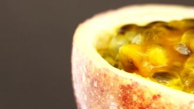 Gözbebeği tutkusunun 4K enine kesiti. Kesilmiş taze egzotik tutku meyvesi Macro shot 'ı. Siyah arka planda izole bir şekilde dönüyor.