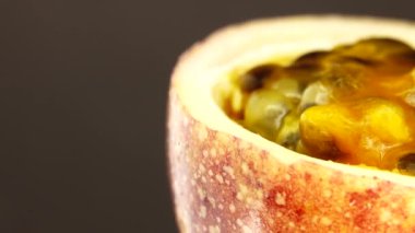 Gözbebeği tutkusunun 4K enine kesiti. Kesilmiş taze egzotik tutku meyvesi Macro shot 'ı. Siyah arka planda izole bir şekilde dönüyor.