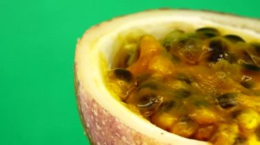 Gözbebeği tutkusunun 4K enine kesiti. Dilimlenmiş taze egzotik çarkıfelek meyvesi Macro shot 'ı. CG yeşil arka planda izole edilmiş.