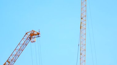 4K large construction site with several busy cranes at dusk with clear blue sky