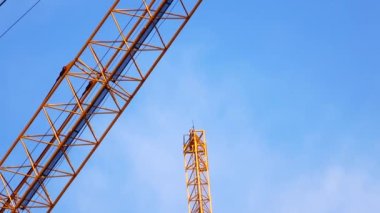4K large construction site with several busy cranes at dusk with clear blue sky