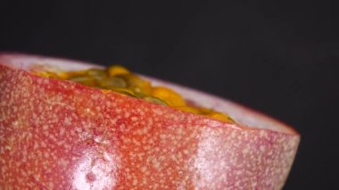 Gözbebeği tutkusunun 4K çapraz kesiti. Kesilmiş taze egzotik tutku meyvesi Macro shot 'ı. Siyah arka planda izole edilmiş.