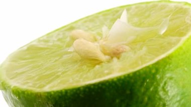 Yeşil limonun 4K dönüşü. Üst görünüm, 360 derece döndürme, beyaz arkaplanda izole edilmiş bir kesikte limonun yakın çekimi