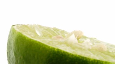Yeşil limonun 4K dönüşü. Üst görünüm, 360 derece döndürme, beyaz arkaplanda izole edilmiş bir kesikte limonun yakın çekimi