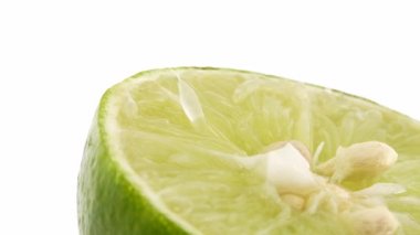 Yeşil limonun 4K dönüşü. Üst görünüm, 360 derece döndürme, beyaz arkaplanda izole edilmiş bir kesikte limonun yakın çekimi