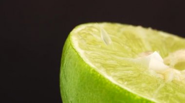Yeşil limonun 4K dönüşü. Üst görünüm, 360 derece döndürme, siyah arkaplanda izole edilmiş bir kesikte limonun yakın çekimi