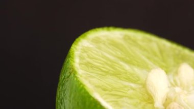 Yeşil limonun 4K dönüşü. Üst görünüm, 360 derece döndürme, siyah arkaplanda izole edilmiş bir kesikte limonun yakın çekimi