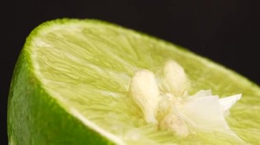Yeşil limonun 4K dönüşü. Üst görünüm, 360 derece döndürme, siyah arkaplanda izole edilmiş bir kesikte limonun yakın çekimi