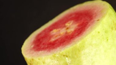 4K makro organik dilimlenmiş guava döner levhayı kapat siyah arkaplanda izole edilmiş.