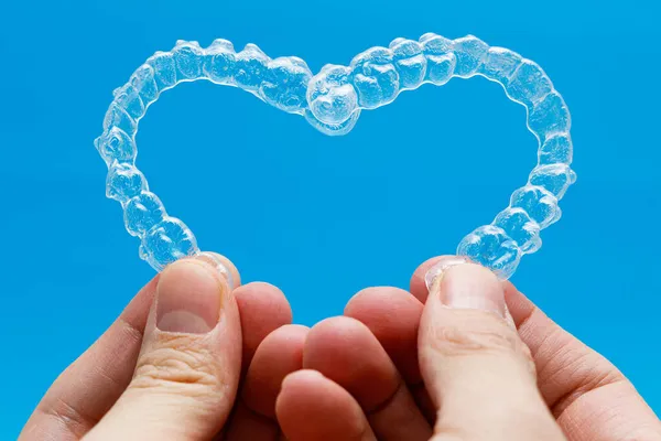Mãos Segurando Alinhadores Dentários Forma Coração Fundo Azul — Fotografia de Stock