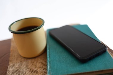 Sarı kahve fincanları, telefonlar ve kitaplar evdeki ahşap masada..