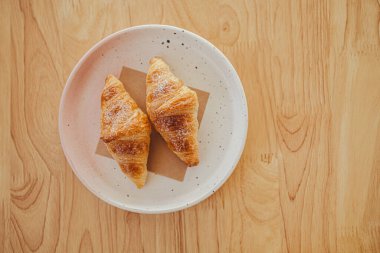 Bir tabakta iki iştah açıcı kruvasan kafedeki ahşap bir masaya konur..