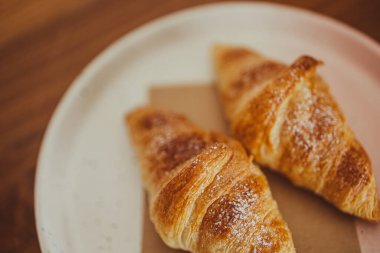 Bir tabakta iki iştah açıcı kruvasan kafedeki ahşap bir masaya konur..