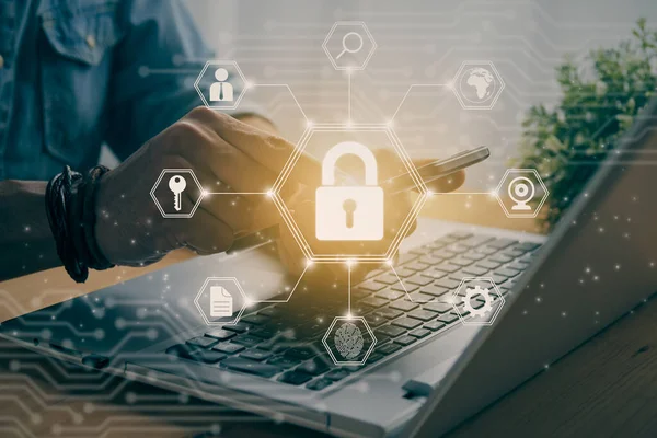Casual Businessman Hand Touching Mobile Phone or Smart Phone Screen and Center Hexagon Lock Security Sign and Laptop Computer. Secure or Firewall and Protection Concept in Vintage Tone