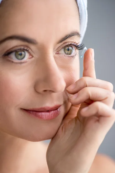 Vrouw in haar veertig invoegen contactlenzen — Stockfoto