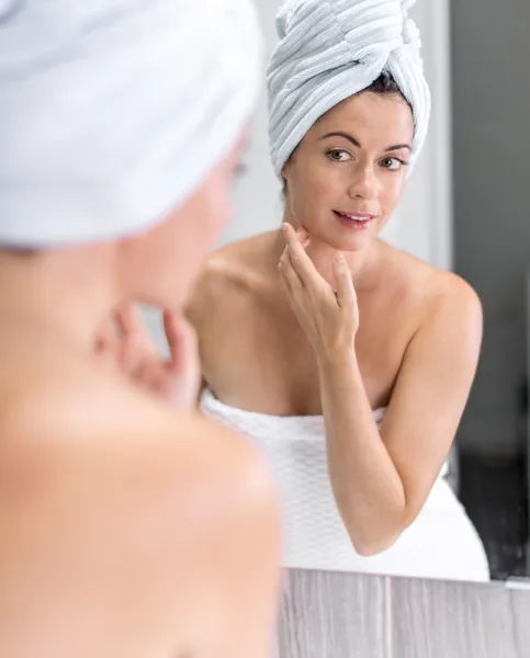 Mujer de mediana edad mirándose en el espejo —  Fotos de Stock