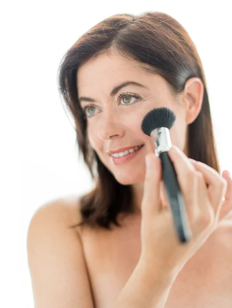 Mulher atraente aplicando maquiagem em seu rosto — Fotografia de Stock