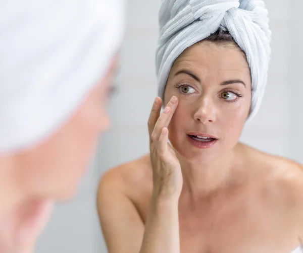 Attraktive Frau mittleren Alters blickt in den Spiegel — Stockfoto