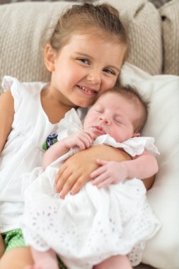 Kız kardeşinin kollarında bir elbiseyle bebek