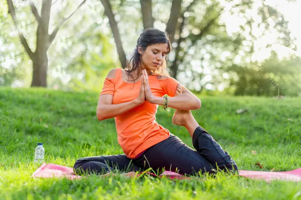 Mulher ativa fazendo poses de ioga ao pôr do sol — Fotografia de Stock