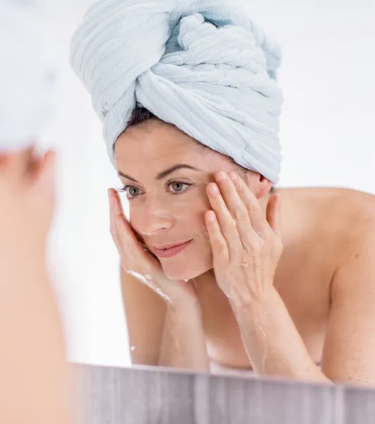 Middle aged woman cleaning her sking over the sink — Stock Photo, Image