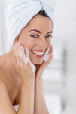 Orta yaşlı kadın onun sking lavabo üzerinde temizlik