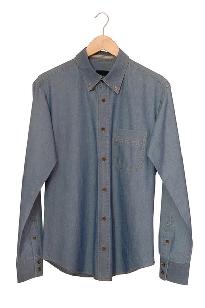 Une chemise en denim bleu est sur le cintre . — Photo