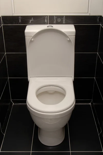 The white toilet bowl is in black interior. — Stock Photo, Image