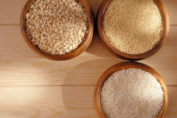 Some oatmeal, millet, rice are in woody bowls. — Stock Photo, Image