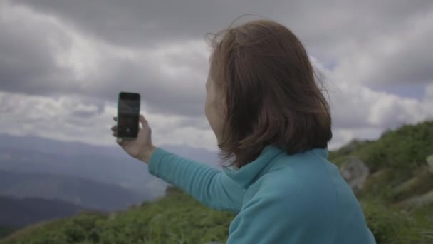 Vrouw neemt foto van het landschap troebele bergen met behulp van mobiele telefoon. Foto maken van landschap. — Stockvideo