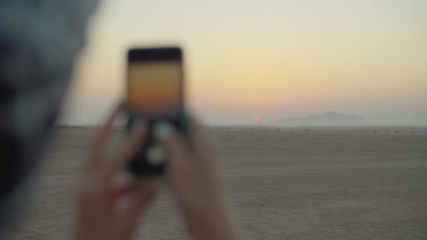 女手在沙漠中的手机上拍摄日出的照片 游客们喜欢沙漠黎明 旅行者拍摄美丽的沙漠日出 — 图库视频影像