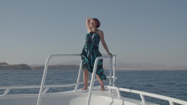 Kobieta 30s w sukience cieszy się widokiem na morze żeglarstwo na łodzi. Szczęśliwa zrelaksowana kobieta stojąca na nosie jachtu. — Wideo stockowe