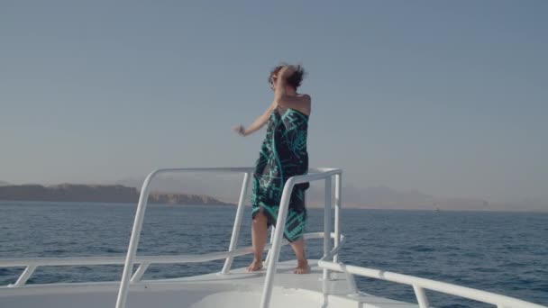 Mujer feliz bailando en la nariz de un yate blanco navegando en el mar. La persona alegre y positiva baila en el barco. — Vídeos de Stock