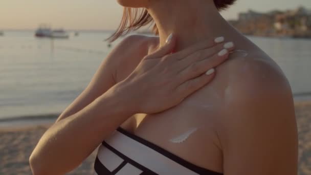 Mujer con protector solar en el cuello de pie en la playa. Ninguna mujer de la cara hidratando su piel con crema de protección solar. — Vídeo de stock