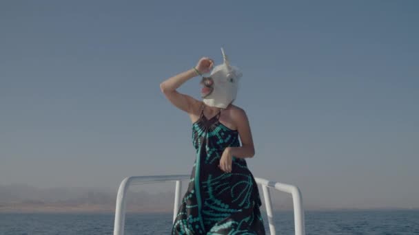 Baile positivo en máscara de cabeza de unicornio en la nariz del yate. Divertido baile de máscara de unicornio en barco en el mar. Felices vacaciones. — Vídeo de stock