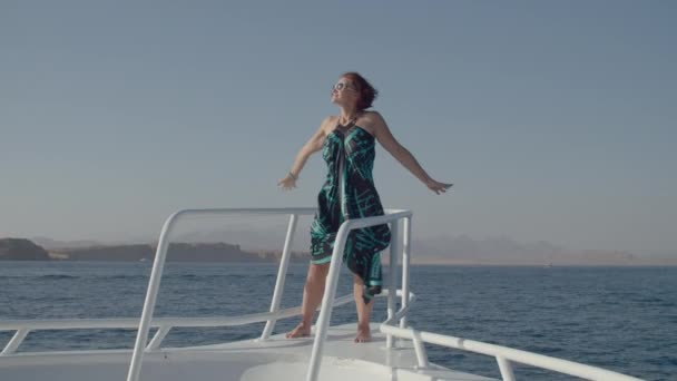 Femme en robe jouit d'une vue sur la mer voile sur yacht. Heureuse femelle détendue debout sur le nez du bateau. Voyage en mer. — Video