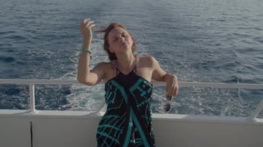 Elbiseli kadın yatla denize açılmaktan hoşlanıyor. Mutlu, rahat bir kadın teknede oturuyor. Deniz yolculuğu.