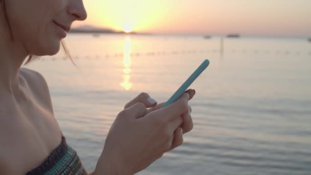 Ręce kobiet korzystających z telefonu komórkowego nad morzem. Kobieta wpisując wiadomość trzymając komórkę w rękach o wschodzie słońca nad morzem. — Wideo stockowe