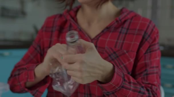 Las manos femeninas comprimiendo botellas de plástico mientras clasifican los residuos reciclables en casa. Exprimir botellas de plástico antes de reciclarlas. Salvar el concepto del planeta. — Vídeo de stock